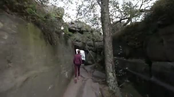 Mulher feliz corre através de um passe turístico entre rochas e pedras para um deck de observação. Rastreamento tiro com câmera estabilizada — Vídeo de Stock