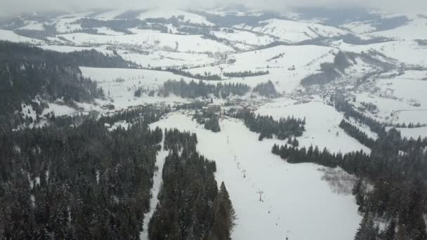 Flug über ein Skigebiet in den Karpaten. Luftaufnahme schneebedeckter Häuser in den Bergen. — Stockvideo