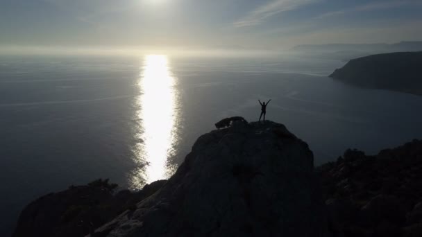 Vuelo sobre una joven mujer de pie en la cima de una montaña frente al mar. Señora en la cumbre en un hermoso paisaje . — Vídeos de Stock