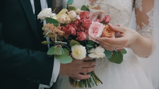 El novio está celebrando un hermoso ramo de bodas. La novia está tocando flores. Ramo de novia en el día de la boda . — Vídeos de Stock