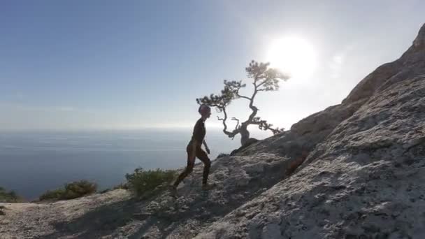 Mujer joven escalando y llegando a la cima de una montaña. Señora en la cumbre en un hermoso paisaje . — Vídeos de Stock