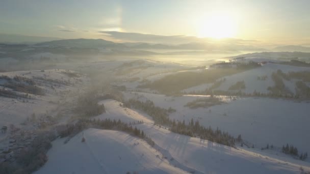 Vista aérea de montañas cubiertas de nieve. Paisaje rural en invierno. Vuelo sobre un pueblo en las montañas Cárpatas . — Vídeo de stock