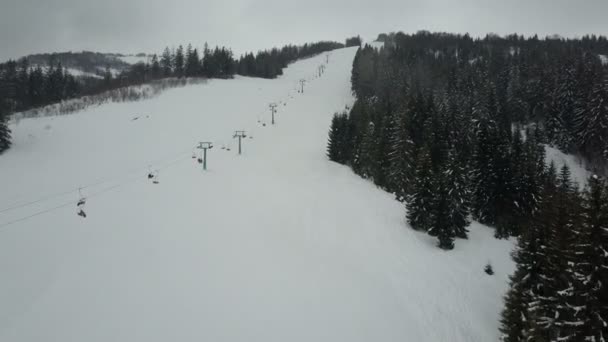 Vuelo sobre un telesilla en las montañas Cárpatas. Vista aérea de personas que descienden sobre esquís . — Vídeo de stock