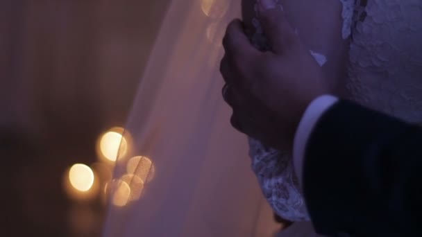 Pareja de boda cogida de la mano delante de una ventana — Vídeo de stock