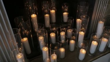 Dekore edilmiş bir baca yakınındaki yüksek bardaklarda mumlar yanan