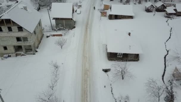 Schneller Flug über eine Straße in einem Karpatendorf. Vogelperspektive auf schneebedeckte Häuser. ländliche Landschaft im Winter. Karpaten-Dorf im Schnee aus der Höhe. — Stockvideo