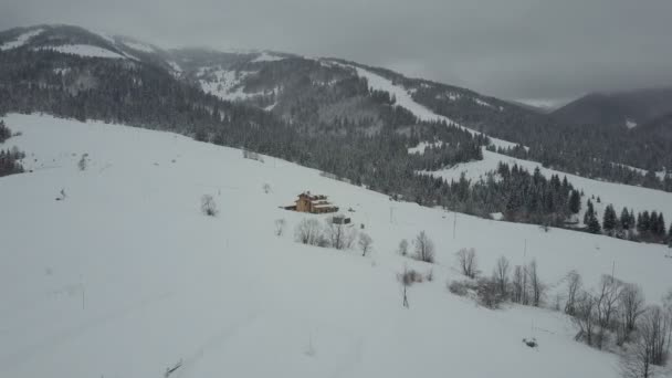 Flygning över en by i Karpaterna. Birds eye view av snötyngda hus i bergen. Landsbygdens landskap på vintern. Karpaterna village i snön från en höjd. — Stockvideo