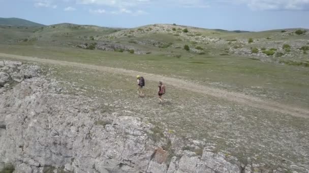 Dos muchachas que caminan en las montañas al borde de un acantilado impresionante en la Crimea — Vídeos de Stock