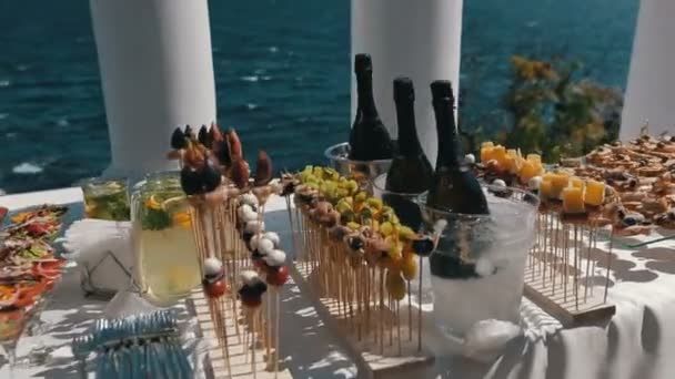 Стол регистрации с бокалами, наполненный свежим салатом. Фокусная панорама стола, сервируемого на открытом воздухе у моря — стоковое видео