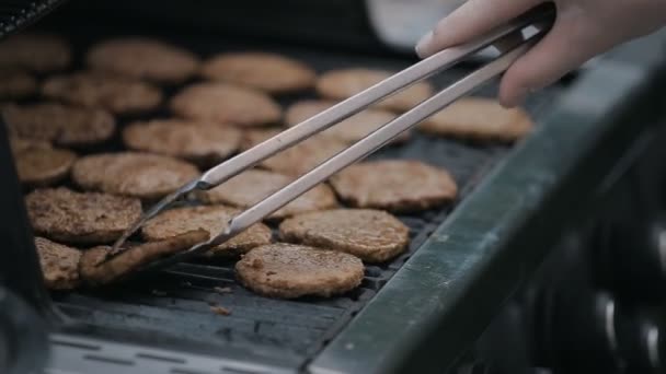 Zbliżenie na Burgery smażenia na grill. Szef kuchni, gotowanie, podrzucanie i skakaniu przez kotlet soczyste mięso z łopatki. — Wideo stockowe