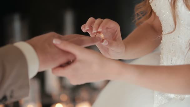 新娘把结婚戒指戴在新郎的手指上。婚姻的手与戒指。新娘和新郎交换结婚戒指. — 图库视频影像