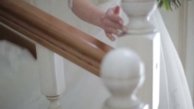 Güzel gelin merdivenlerden aşağı yürüyüş, yakın çekim. Beyaz elbiseli kadın merdivenlerden geliyor. Ağır çekim