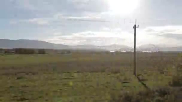 Vista lateral de la ventana del coche del paisaje rural, montañas y lago al atardecer. Conducción por carretera rural a lo largo de la línea eléctrica . — Vídeo de stock