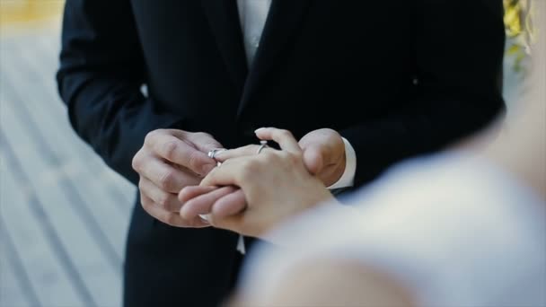 The groom puts the wedding ring on finger of the bride and kisses her hand. The bride and groom exchange wedding rings. — Stock Video