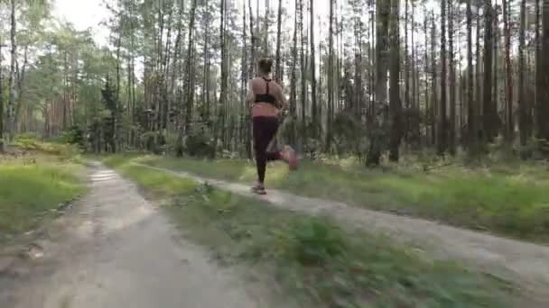 Jovem feliz está correndo em uma floresta entre as árvores. Rastreamento tiro com câmera estabilizada — Vídeo de Stock