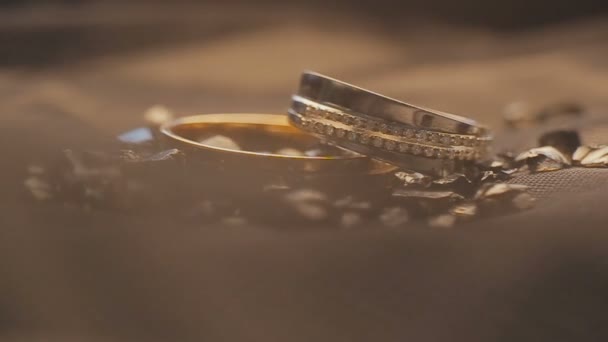 Wedding rings on a decorated surface shining with light close up macro — Stock Video
