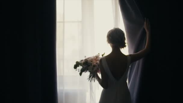 Η όμορφη νύφη μπουκέτο ανοίγει μια κουρτίνα. Σιλουέτα. Εστίαση Πανόραμα. — Αρχείο Βίντεο
