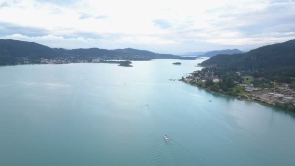 Luchtfoto van een groot meer in de bergen. Boot beweegt op het meer. Klagenfurt, Karinthië. — Stockvideo