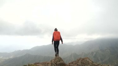 Okyanusun üstündeki kaktüsler arasında dağlarda yüksek yürüyen genç kadın. Güzel sahne zirvesinde Lady Kanarya Adaları, Tenerife bir yüksekliği okyanus gözlem.