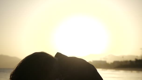 Slow Motion Primer plano silueta de la joven mujer moviendo la cabeza con el pelo soplando en el viento mirando la puesta de sol sobre el océano . — Vídeos de Stock