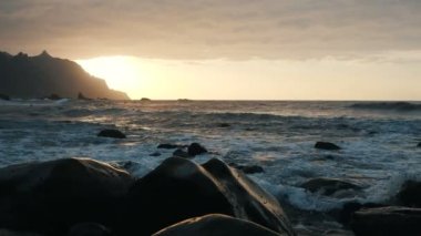 Okyanus dalgaları, Tenerife, Kanarya Adaları 'ndaki Benijo plajında, güzel gün batımı ışığında kayalar ve sprey üzerinde çökme