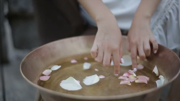 Meisjes handen aanraken rozenblaadjes in een ronde badkuip. — Stockvideo