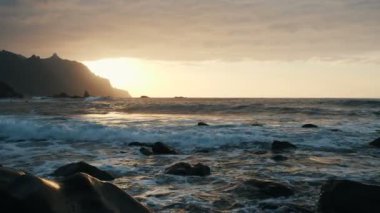 Okyanus dalgaları, Tenerife, Kanarya Adaları 'ndaki Benijo plajında, güzel gün batımı ışığında kayalar ve sprey üzerinde çökme