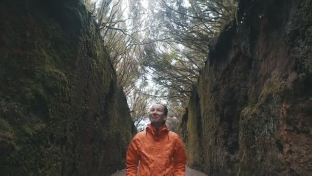 Giovane donna felice ottimista cammina lungo una strada tra le rocce nel parco naturale Anaga a Tenerife. Forte vento muove rami di alberi — Video Stock