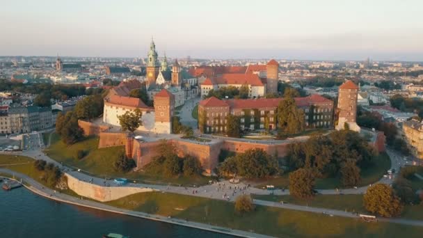 Vista aérea da Catedral Real de Wawel e castelo em Cracóvia, Polônia, com o rio Vístula, parque, quintal e turistas ao pôr-do-sol. Cidade velha no fundo — Vídeo de Stock