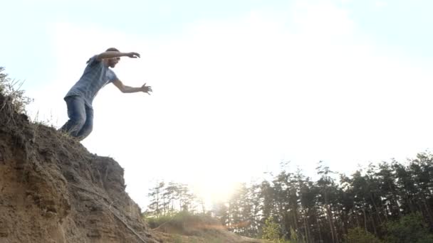 El hombre salta en una arena en cámara lenta al aire libre al atardecer . — Vídeos de Stock