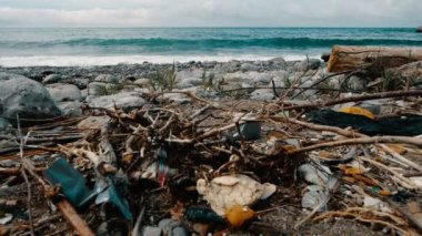 Çöp, plastik, çöp, sahilde çevre kirliliği. Arka planda yavaş hareket dalgaları. Çöp, plajda plastik şişe. Okyanus ortamını kirleten atık