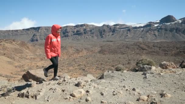 Mujer joven caminando en lo alto de las montañas y observando un enorme cráter del volcán Teide en Tenerife, Islas Canarias, España . — Vídeo de stock