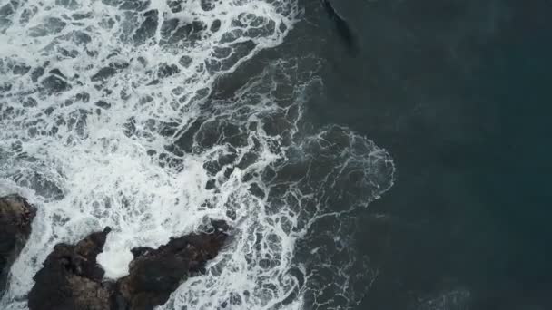 Vista aérea superior das ondas do oceano que quebram em rochas escuras na praia de areia preta, Ilhas Canárias, Tenerife, Espanha — Vídeo de Stock