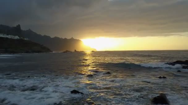 Flug über Meereswellen mit Blick auf den wunderschönen Sonnenuntergang und die Berge am Horizont. Drohnenaufnahme des schönen Sonnenuntergangs am Strand von Benijo auf Teneriffa, Kanarische Inseln, Spanien — Stockvideo
