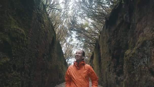 Giovane donna felice ottimista cammina lungo una strada tra le rocce nel parco naturale Anaga a Tenerife. Forte vento muove rami di alberi — Video Stock