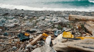 Çöp, plastik, çöp, deniz kıyısında çevre kirliliği. Arka planda yavaş çekimde dalgalar. Çöp, sahilde plastik şişe. Okyanus çevresini kirleten atıklar