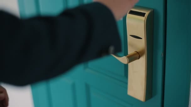 Ο άντρας με το σκούρο μπλε κοστούμι προσπαθεί να ξεκλειδώσει μια τεράστια τιρκουάζ πόρτα με λάθος πλαστικό κλειδί κάρτας. Ο άνθρωπος δεν μπορεί να ξεκλειδώσει μια πόρτα με μια πλαστική κάρτα. Κλείσιμο ενός χερούλι πόρτας. — Αρχείο Βίντεο