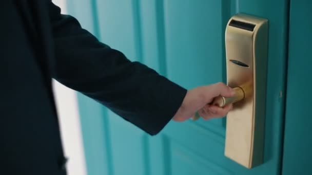 Man in donkerblauw pak opent een enorme Turquoise deur en komt in een kamer. Close-up van een deurklink. — Stockvideo