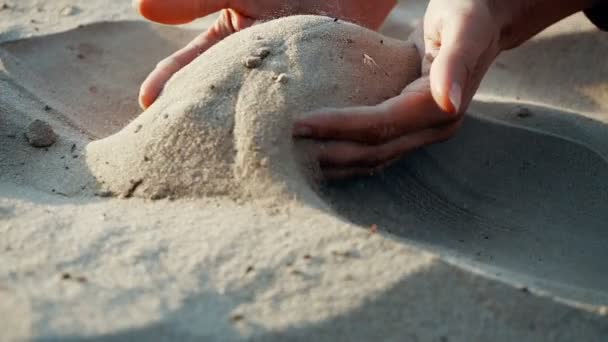 SLOW MOTION, CLOSE UP: The sand passes through the fingers of a young woman. The sand is running through fingers of a lady and is spread by a strong wind. — Stock Video