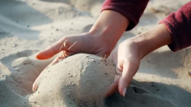 SLOW MOTION, FLOSE UP: A areia passa pelos dedos de uma jovem mulher. A areia está correndo através dos dedos de uma senhora e é espalhada por um vento forte . — Vídeo de Stock