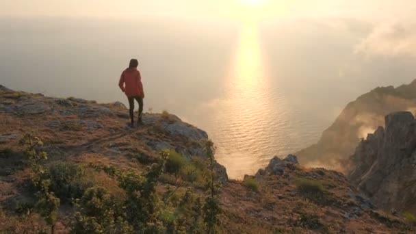 Silhuette van jonge man armen uitgerekt observeren prachtige dramatische kleurrijke zonsondergang boven een zee van een hoge berg in de Krim. — Stockvideo
