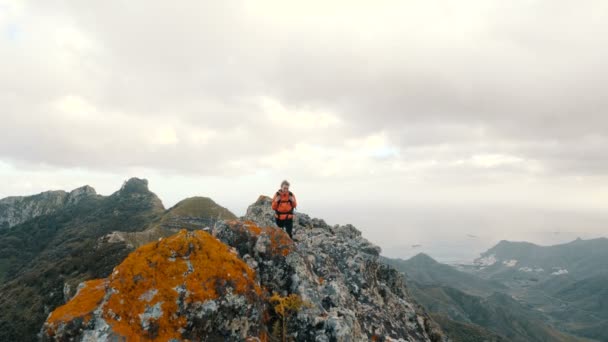 Mujer joven caminando en lo alto de las montañas entre los cactus sobre el océano. Señora en la cumbre observando hermosos paisajes desde una altura en Tenerife, Islas Canarias . — Vídeo de stock