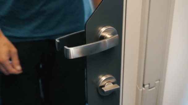 Mans hand unlocks a latch and opens a mirror door with metal handle. Man exits a modern comfortable train compartment. A train passenger closes a mirror door from outside. — Stock Video