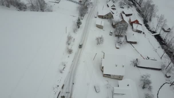 Быстрый перелет над машиной, движущейся по зимней дороге в селе Карпаты. Вид на заснеженные дома с высоты птичьего полета. Сельский пейзаж зимой . — стоковое видео