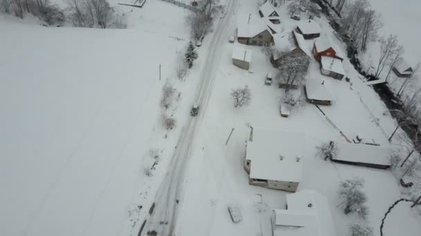 Vuelo rápido sobre un coche que se mueve en carretera de invierno en la aldea de los Cárpatos. Vista de aves de casas cubiertas de nieve. Paisaje rural en invierno . — Vídeos de Stock