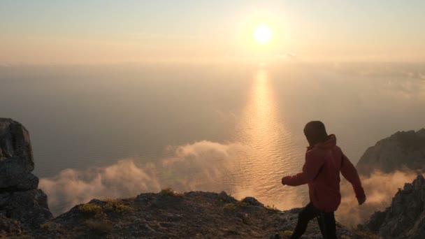 Silhuette van jonge man armen uitgerekt observeren prachtige dramatische kleurrijke zonsondergang boven een zee van een hoge berg in de Krim. — Stockvideo