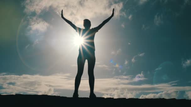 Silhouet van een jonge vrouw die armen uitrekken tegen prachtige hemel en zon. Slow Motion, prachtige zonnestralen. — Stockvideo