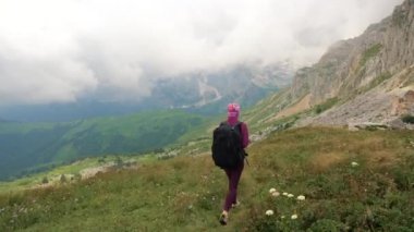 Sırt çantası olan genç kadın güzel Kafkas dağlarında yürüyüş ediyor. Bayan zirveye doğru yürüyor.