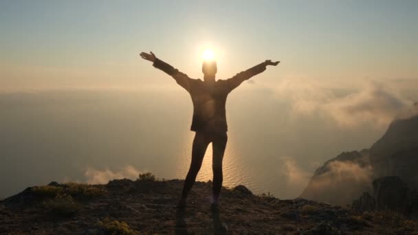 Silhuette Young Woman arms outstretched observing a beautiful dramatic sunset above a sea from a high mountain in Crimea. — Stock Video