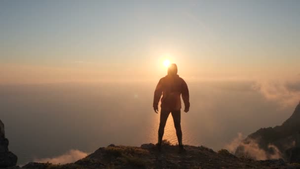 Silhuette de los brazos del hombre joven se extendió observando la hermosa puesta de sol dramática y colorida sobre un mar desde una alta montaña en Crimea . — Vídeo de stock